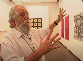Foto do artista plástico brasileiro Nelson Leirner numa exposição com suas obras