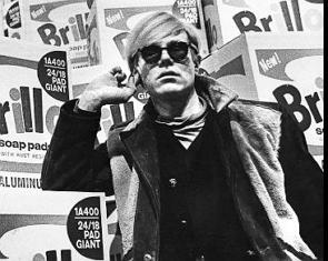 Foto de Andy Warhol em frente a uma de suas obras de arte