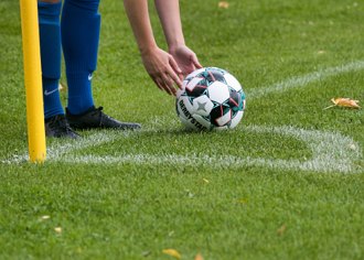 Imagem de um jogador preparando a bola para a cobrança de escanteio.