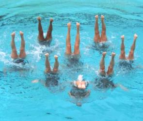 Nadadoras fazendo coreografia numa piscina numa prova de nado sincronizado