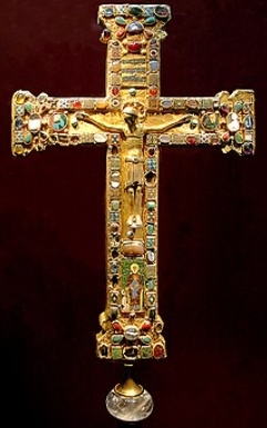 Cruz dourada, enfeitada com pedras preciosas e imagem de Jesus ao centro