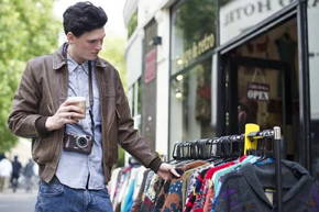 Foto de um consumidor analisando roupas numa loja
