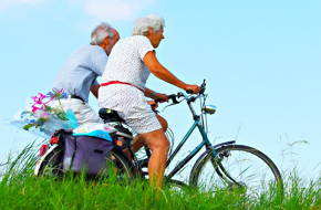 Foto de um casal de idosos andando de bicicleta.