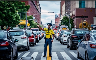 Ilustração mostrando um agente de trânsito, orientando os motoristas numa rua.