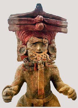 Foto de uma escultura maia representando uma pessoa usando uma espécie de chapéu