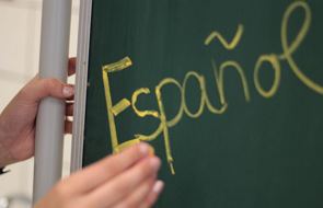 Lousa e uma mão com a palavra escrita Español