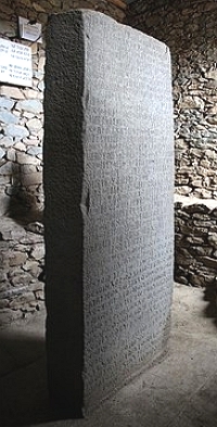 Estela, pedra negra de formato retangular com inscrições