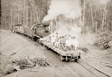 Ferrovia Madeira-Mamoré Foto em preto e branco de uma locomotiva soltando fumaça e pessoas na frente dela