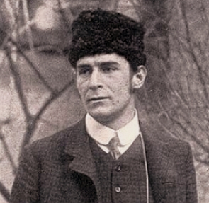 Foto em preto e branco de Franz Marc, homem de meia idade, branco, com chapéu preto na cabeça, num local com galhos secos de árvores