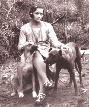Foto de Maria Bonita sentada com dois cachorros ao lado