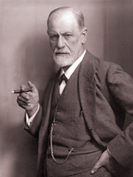 Foto de Freud, homem idoso de barba branca e calvo, segurando um charuto e vestindo terno e gravata.