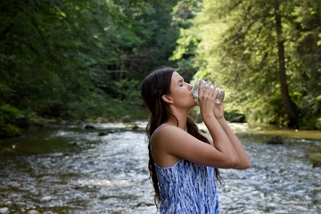 Foto de uma mulher bebendo &aacute;gua na natureza