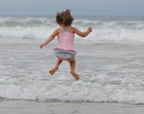 Menina pulando ondas na praia
