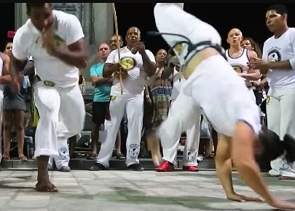 Pessoas vestidas de branco praticando capoeira