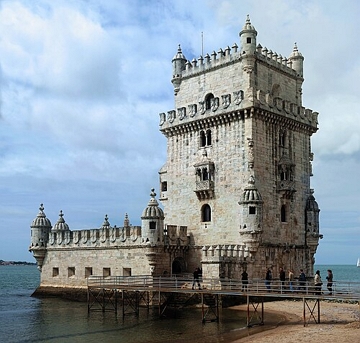 Foto de uma torre de cor cinza claro no formato quadrado com c&eacute;u azul ao fundo